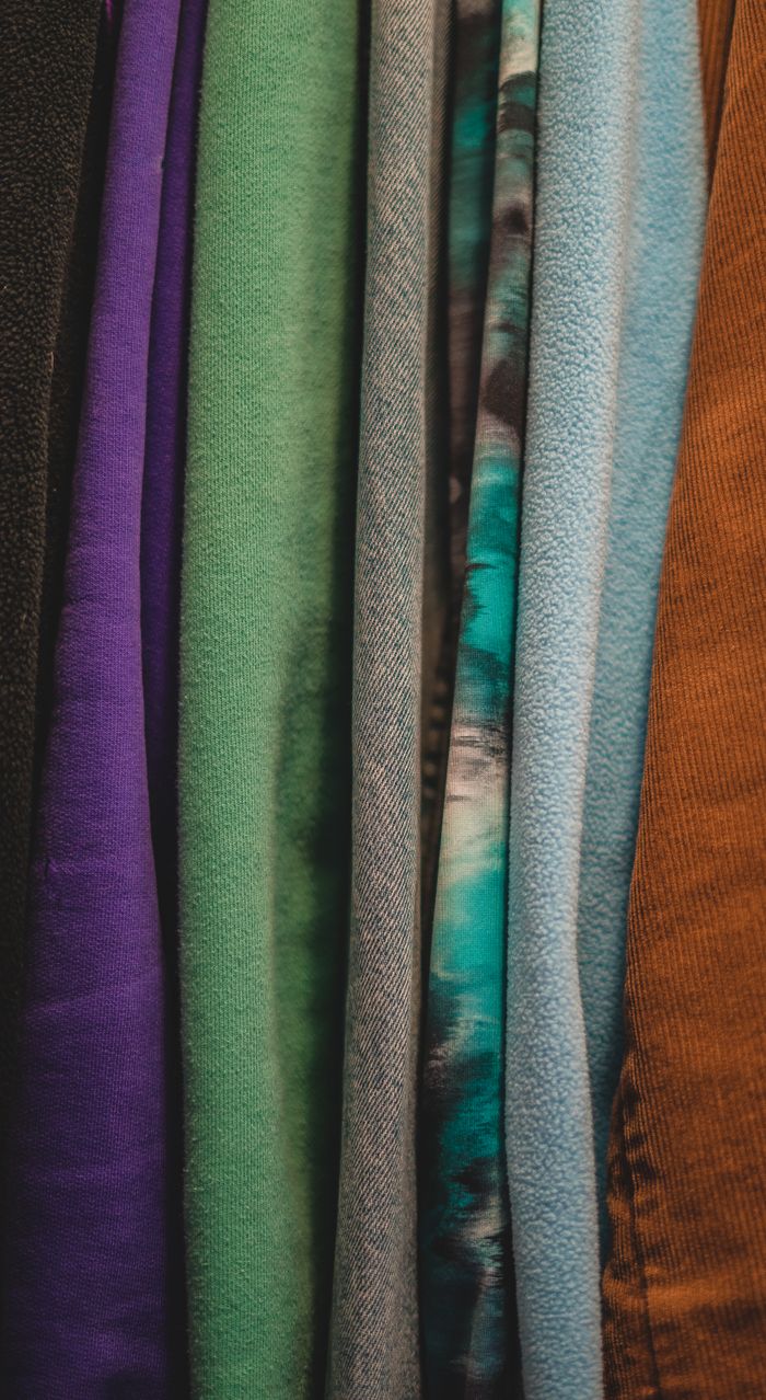 our-services-01 A vibrant collection of various textiles hanging in a vertical arrangement showcasing diverse textures and colors.