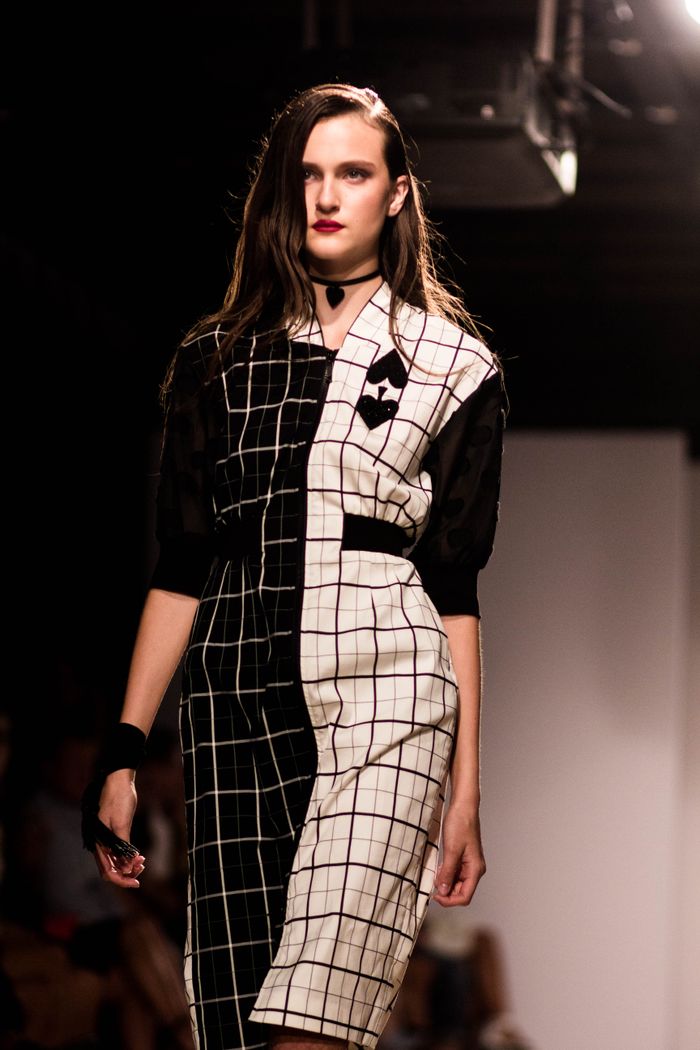 A stylish model walks the runway in a modern checked dress, showcasing contemporary fashion.