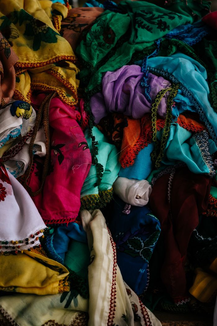 our-services-02 A colorful assortment of intricate fabrics displayed in an Ankara market.